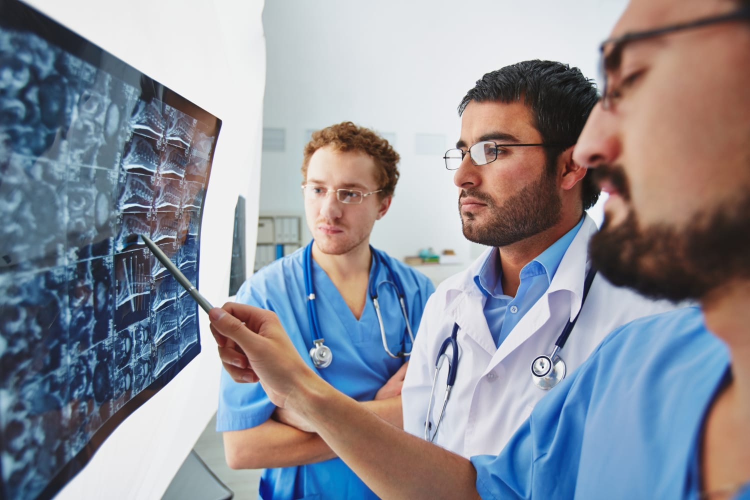 Médico, técnico e residente discutindo possíveis achados em um exame de imagem.